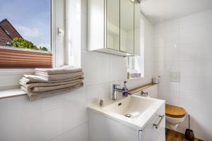 a white bathroom with a sink and a window at Ferienwohnung Halunder in Leck