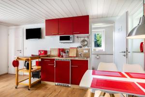 a kitchen with red cabinets and a table and chairs at Ferienwohnung Halunder in Leck +14 photos