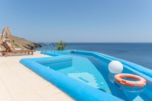 a blue swimming pool next to the ocean at Caldera Studios in Astypalaia