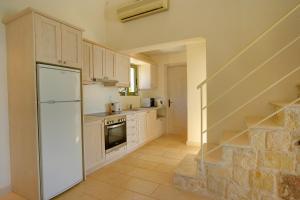 a kitchen with a white refrigerator and a staircase at Villa Petalida Ideales Resort in Kefallonia