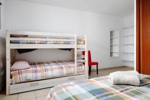 a bedroom with a white bunk bed and a red chair at Finca El Refugio in Teguise