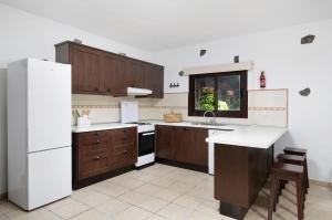 a kitchen with wooden cabinets and a white refrigerator at Finca El Refugio in Teguise +14 photos