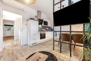 a kitchen with white cabinets and a flat screen tv at Cosy Apartment In Soltau in Soltau