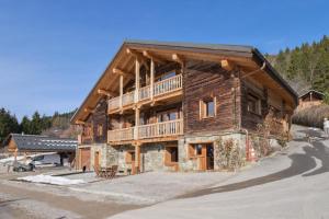 a large wooden house with a balcony on the side at Appartement dans le Chalet l'Albert in Manigod
