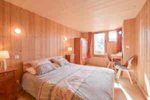 a bedroom with a bed in a wooden room at Appartement dans le Chalet l'Albert in Manigod
