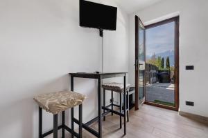a room with a table and two stools and a television at Casa Zoe in Arco