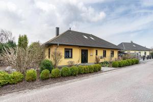 ein gelbes Haus mit schwarzem Dach an einer Straße in der Unterkunft Dreamliner in Sassnitz