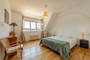 a bedroom with a bed and a chair and a window at Évasion marine face à la mer in Plouézocʼh