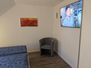 a room with a chair and a tv on the wall at Ferienwohnung Auszeit in Niebüll