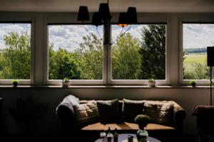 a couch sitting in a room with three windows at Ferienwohnung Emma in Güntersberge