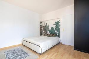 a bedroom with a white bed with a plant on the wall at L'Eclose Chambre Kergoz in Le Guilvinec