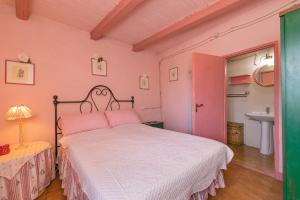 a pink bedroom with a bed and a sink at Casina nel Borgo Antico in Bibbona