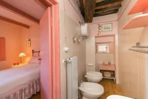 a bathroom with a bed and a toilet in a room at Casina nel Borgo Antico in Bibbona +15 photos