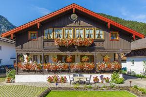 a house with lots of flowers in front of it at Ferienwohnungen Weiß in Mittenwald
