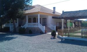 a white house with a porch and a fence at Chalet Del Sol in Puerto Lumbreras