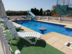 a swimming pool with two chairs and a slide at Chalet Del Sol in Puerto Lumbreras
