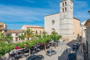 a church with a clock tower next to a street at Maca Green, Adosado Centro Campanet in Campanet