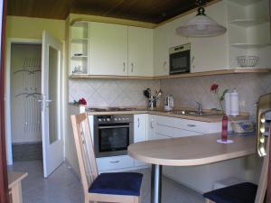a kitchen with white cabinets and a table in it at Ferienwohnung Evi Opp - Harmonie in Brodersdorf