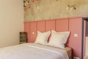 a bed with a pink headboard and white pillows at Charmant Cottage - Saint-Junien in Saint-Junien
