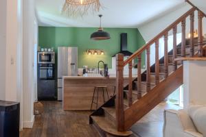 a kitchen with green walls and a wooden staircase at Charmant Cottage - Saint-Junien in Saint-Junien