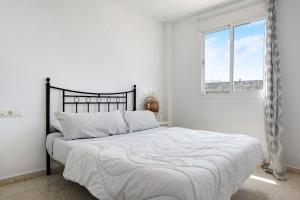 a white bedroom with a large bed with a window at Surfer Tarifa in Tarifa