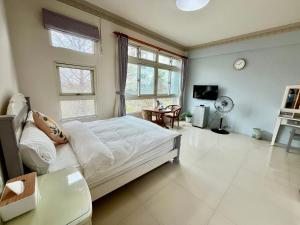 a bedroom with a bed and a table and windows at 花蓮統一的家民宿The home place in Ji'an