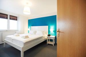 a bedroom with a white bed and a blue wall at Haus Strandeck Nordstrand 18 in Göhren