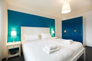 a bedroom with a large white bed with blue walls at Haus Strandeck Nordstrand 18 in Göhren