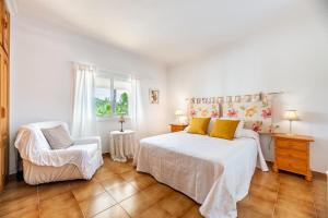a white bedroom with a bed and a chair at Villa Can Andreuet de Baix in Illes Balears +17 photos