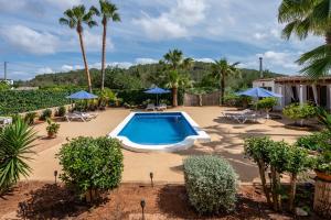 a pool in a yard with palm trees and umbrellas at Villa Can Andreuet de Baix in Illes Balears
