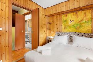 a bedroom with a white bed and a painting on the wall at La Maisonnette in Valtournenche