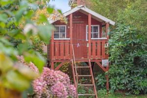 a red tree house with a ladder in a garden at Haus Margarete Christel Winkelmann in Cuxhaven