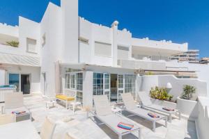 a patio with white chairs and a building at Deluxe Apartment with Jacuzzi in Marbella