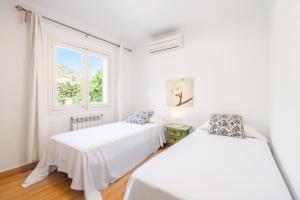 two beds in a white room with a window at Villa Sant Vicente in Cala de Sant Vicenc +20 photos