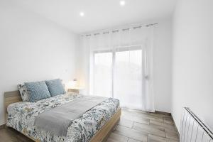 a white bedroom with a bed and a window at Guesthouse dos Limites in Espinho