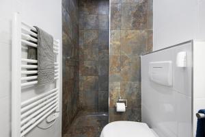 a bathroom with a toilet and a tiled wall at Guesthouse dos Limites in Espinho +18 photos