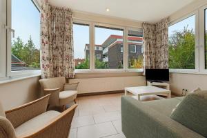 a living room with a couch and chairs and windows at Haus Margarete Christel Winkelmann in Cuxhaven