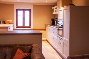 a kitchen with white cabinets and a couch in it at Fewo Hohe Liebe in Rathmannsdorf +13 photos