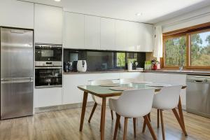 a kitchen with white cabinets and a table and chairs at Vermarl - Viana do Castelo in Linhares de Cima