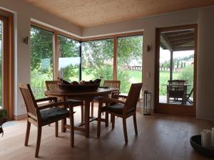 a dining room with a table and chairs and windows at Haus am Teich mit privater Sauna in Sankt Leonhard bei Freistadt
