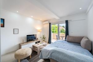 a bedroom with a bed and a couch and a television at Apartments Kankaras - Sea View in Tivat