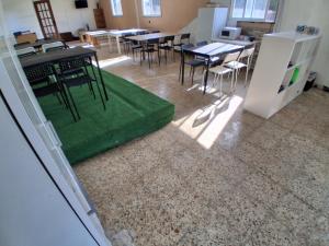 a room with tables and chairs and a green floor at Atlantic Surfers Hostel in Carballo