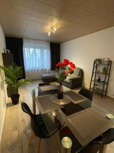 a living room with a couch and a table with red flowers at Ruhige Ferienwohnung Zeithain in Zeithain
