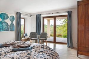 a bedroom with a bed and chairs and a sliding glass door at Casa Rea in Murazzano