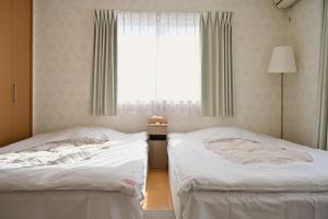 two beds in a room with a window at 心宿 伏見稲荷 in Kyoto