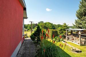 a garden with red flowers next to a red building at Ferienhaus Ton Sünhus in Groß Labenz