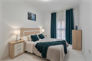 a bedroom with a bed with blue pillows and a window at Apartamento Bonjour in Candelaria