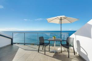 a patio with a table and chairs and an umbrella at The Wave House - Oceanfront in Jardim do Mar
