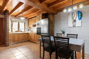 a kitchen with wooden cabinets and a table and chairs at Huerta El Pozu in Soto de las Dueñas