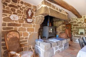 a stone fireplace in a room with a stove at Gîtes Ker Mané in Erdeven